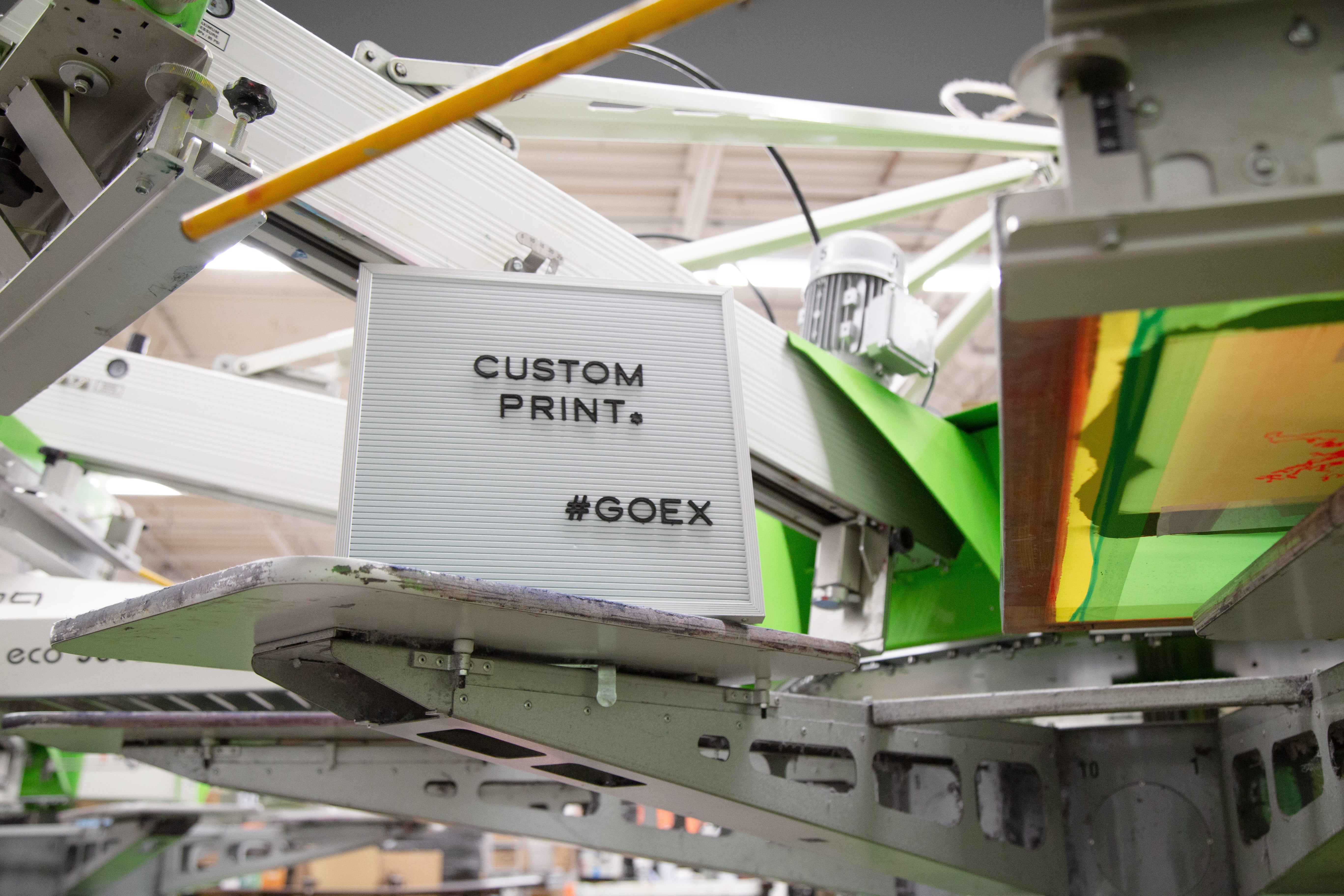 Message board on Printing Press that says "Custom Print. #GOEX"