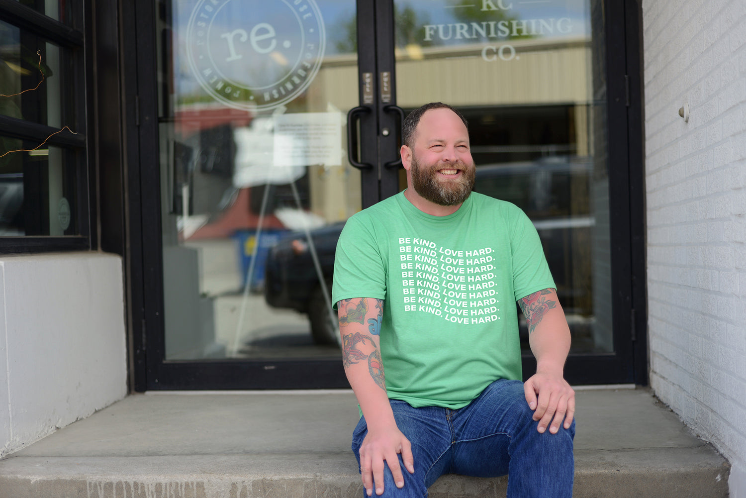 Male Model Sitting on Stairs wearing GOEX Unisex and Men's Eco Triblend tee in Grass with custom graphic