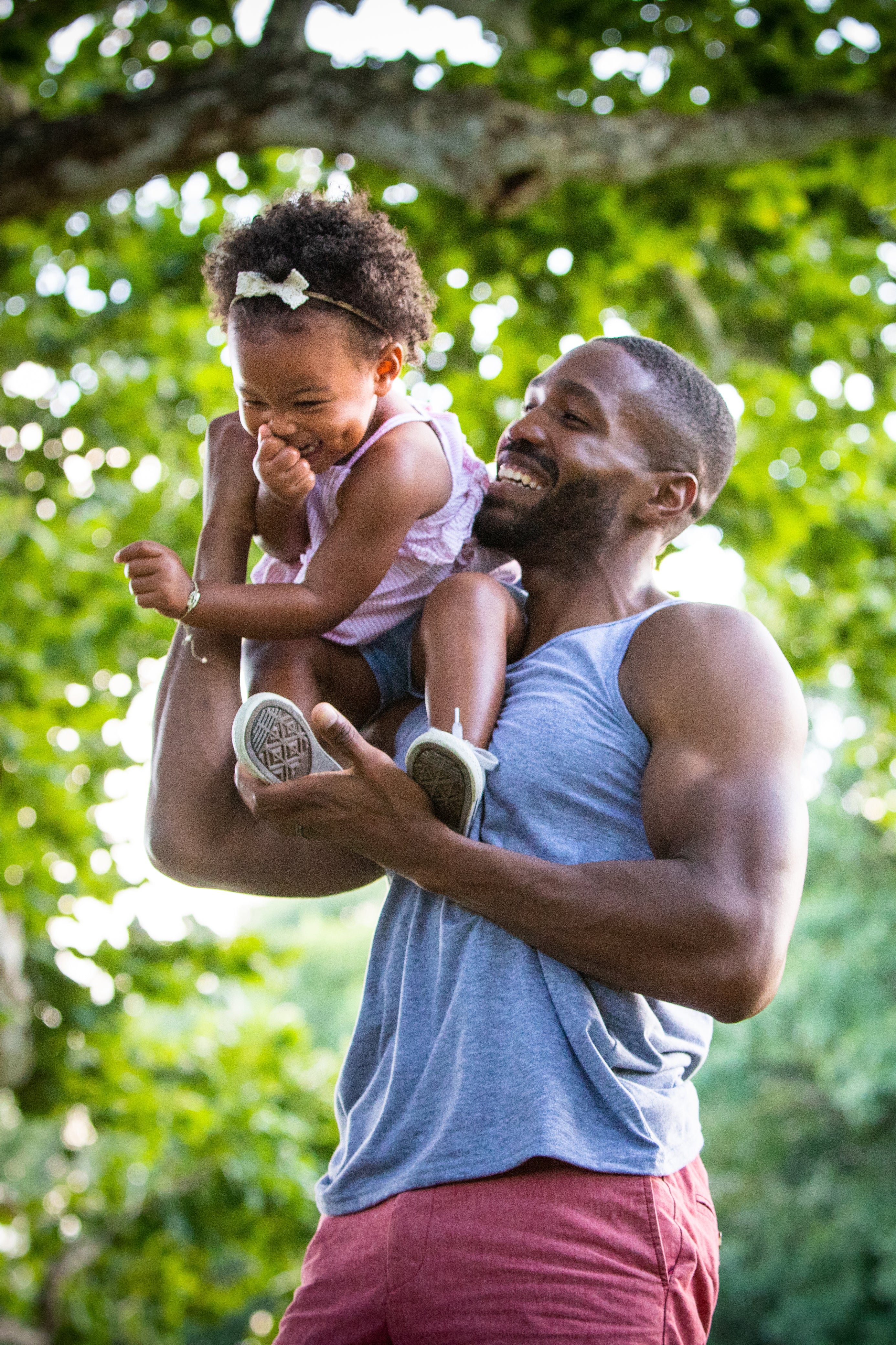 Dad wearing GOEX Unisex and Men's Eco Triblend Tank in Heather Grey while holding toddler 