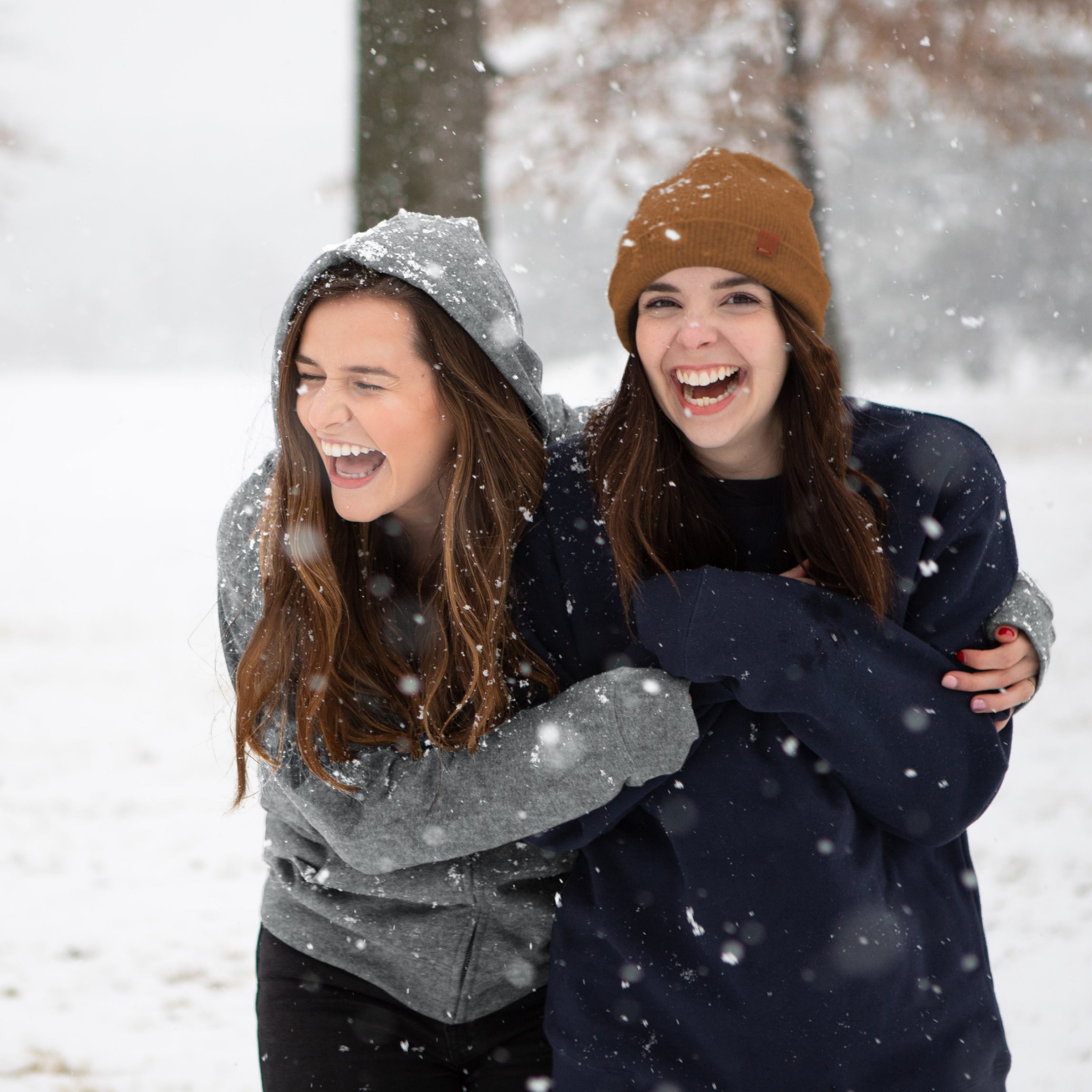 Two women hugging in the snow wearing GOEX Apparel Fleece