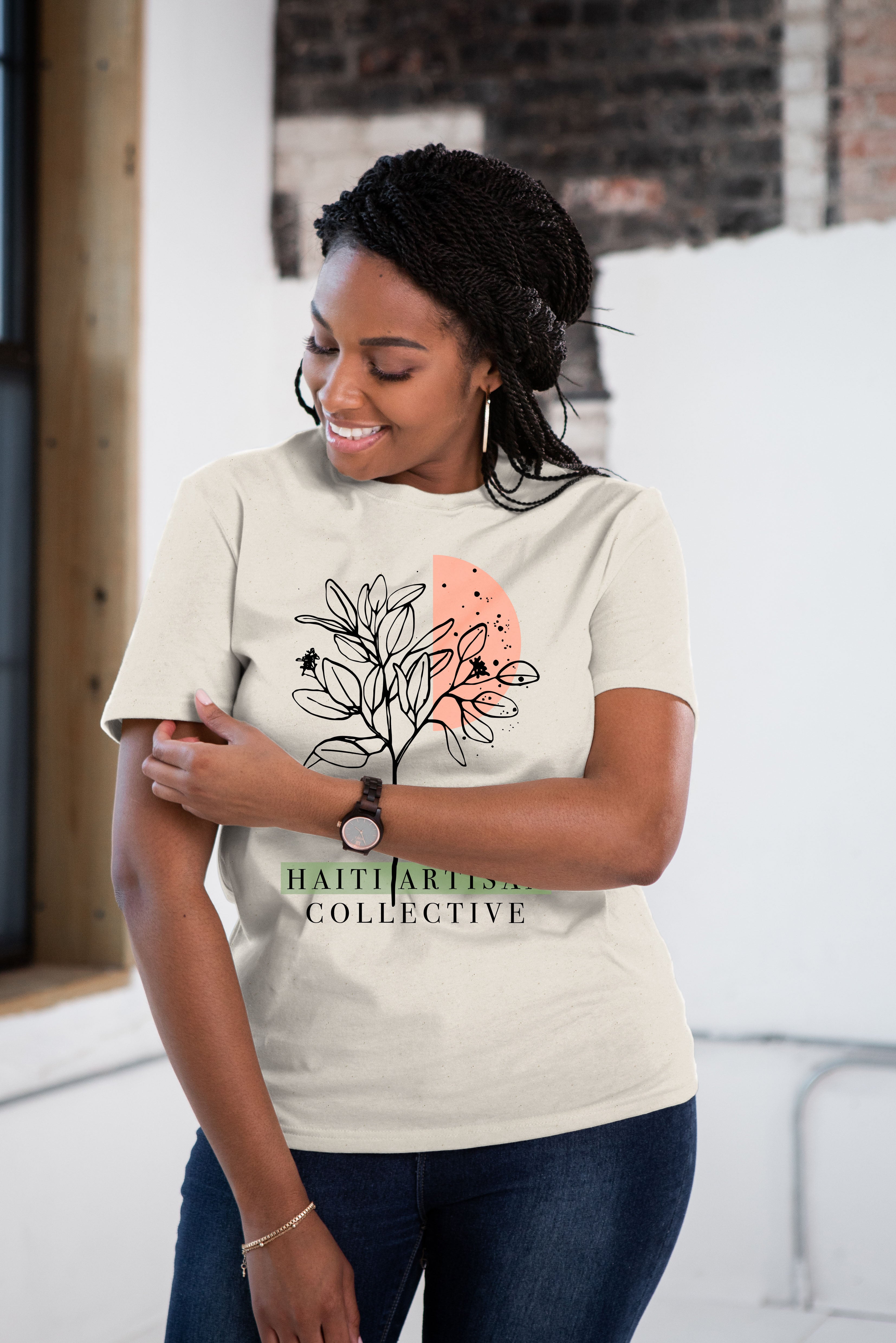 Female model wearing ivory tee with black illustrated flowers and Haiti Artisan Collective logo