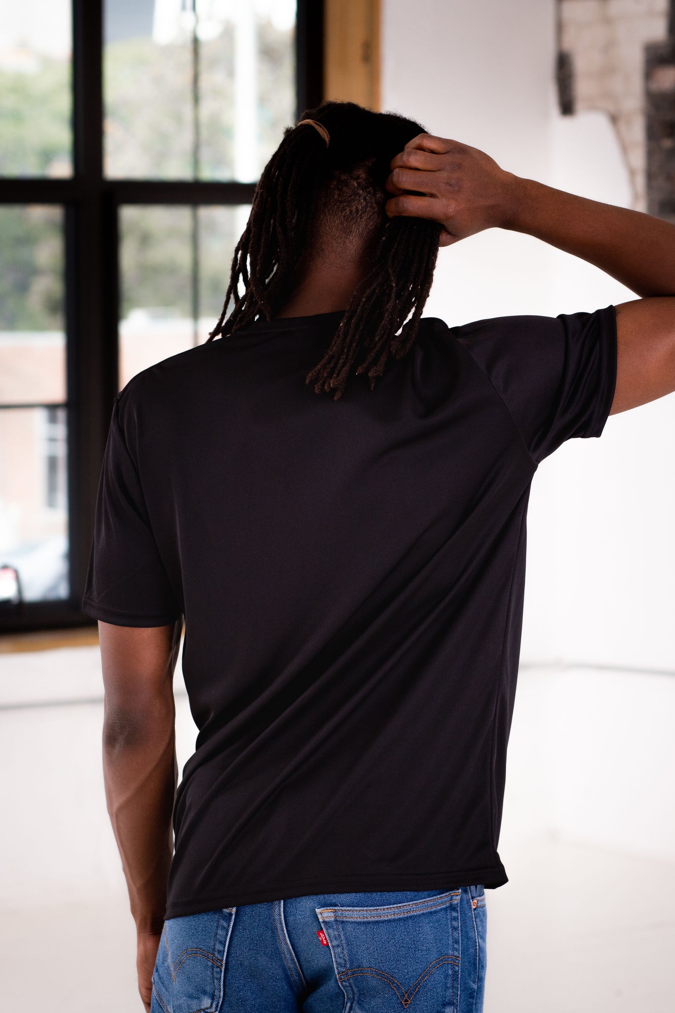 Back View of Male Model wearing GOEX Unisex and Men's Eco Poly Tee in Black