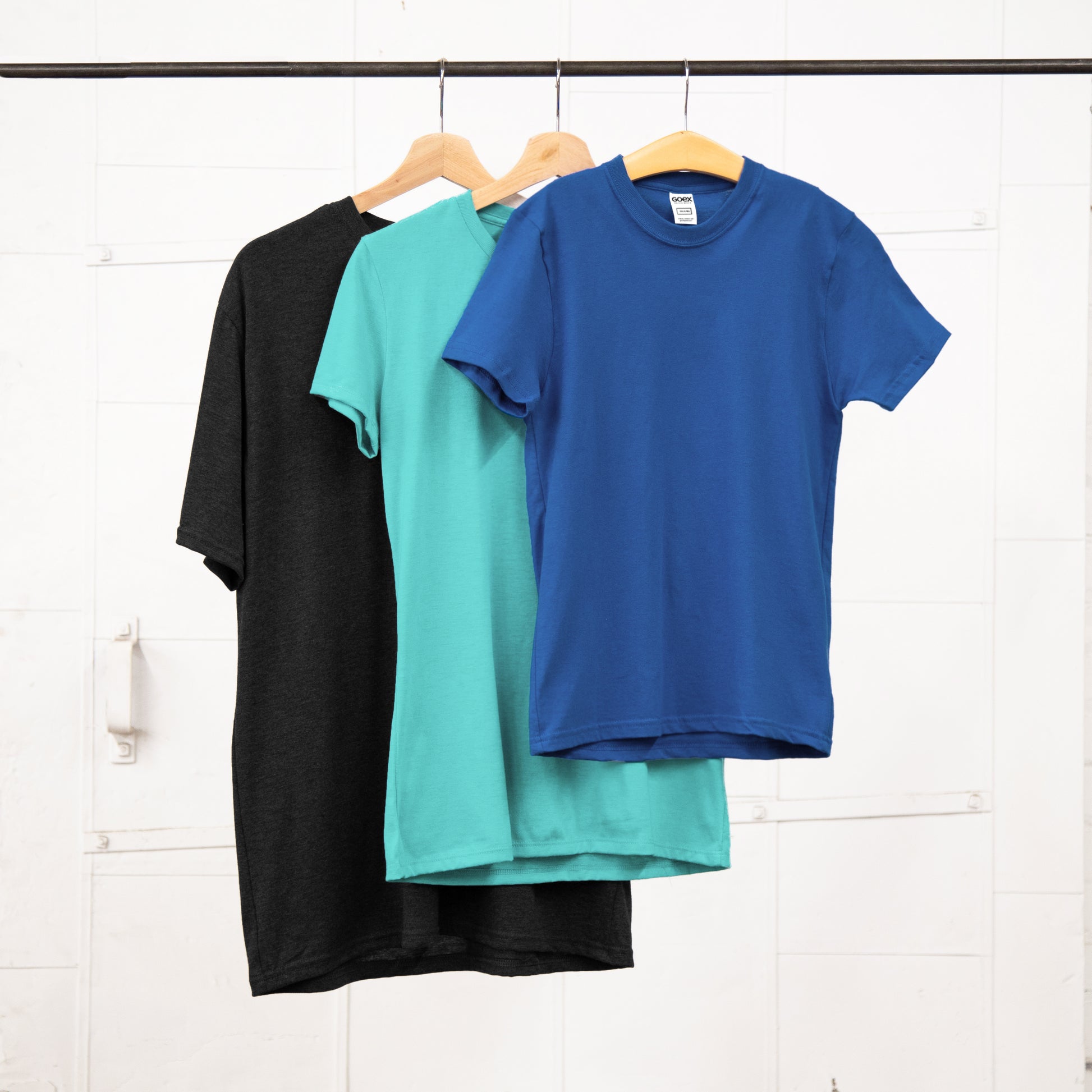 Unisex, Ladies, and Youth tees hanging on a garment rack