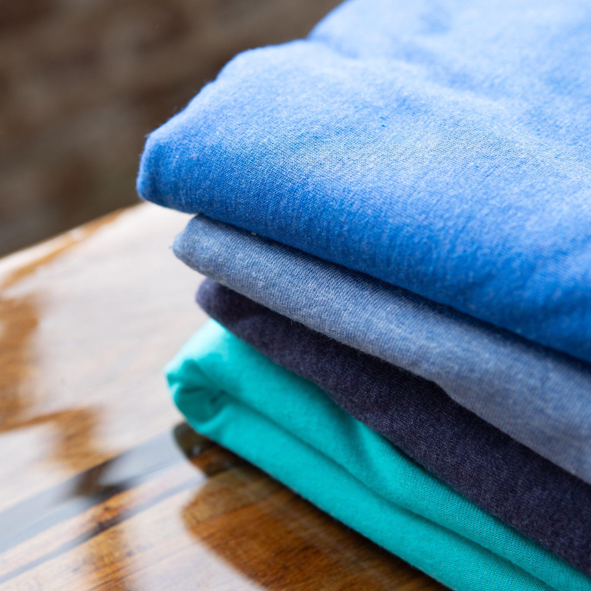 Blue Toned Triblend fabrics stacked on a table